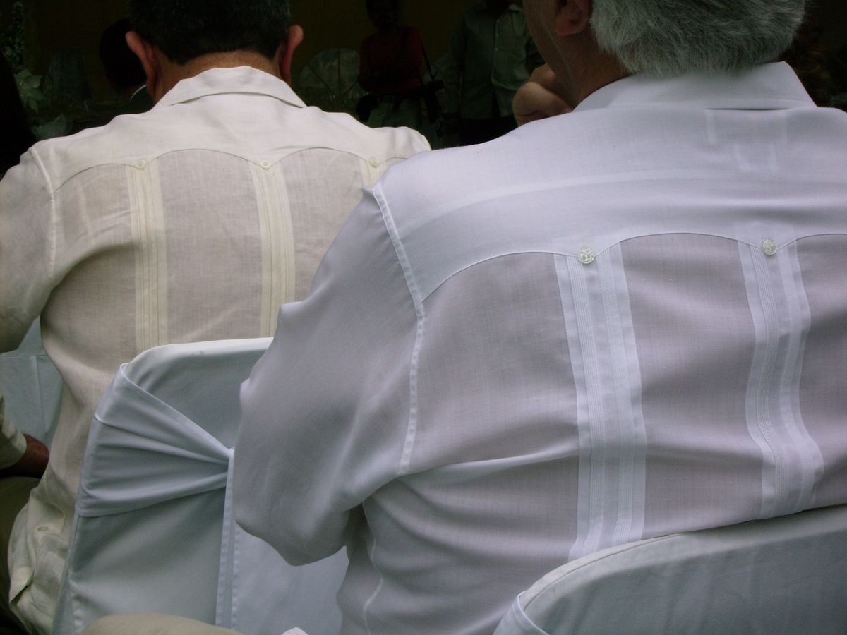 Close-up of two men wearing traditional pleated guayabera shirts, seen from behind