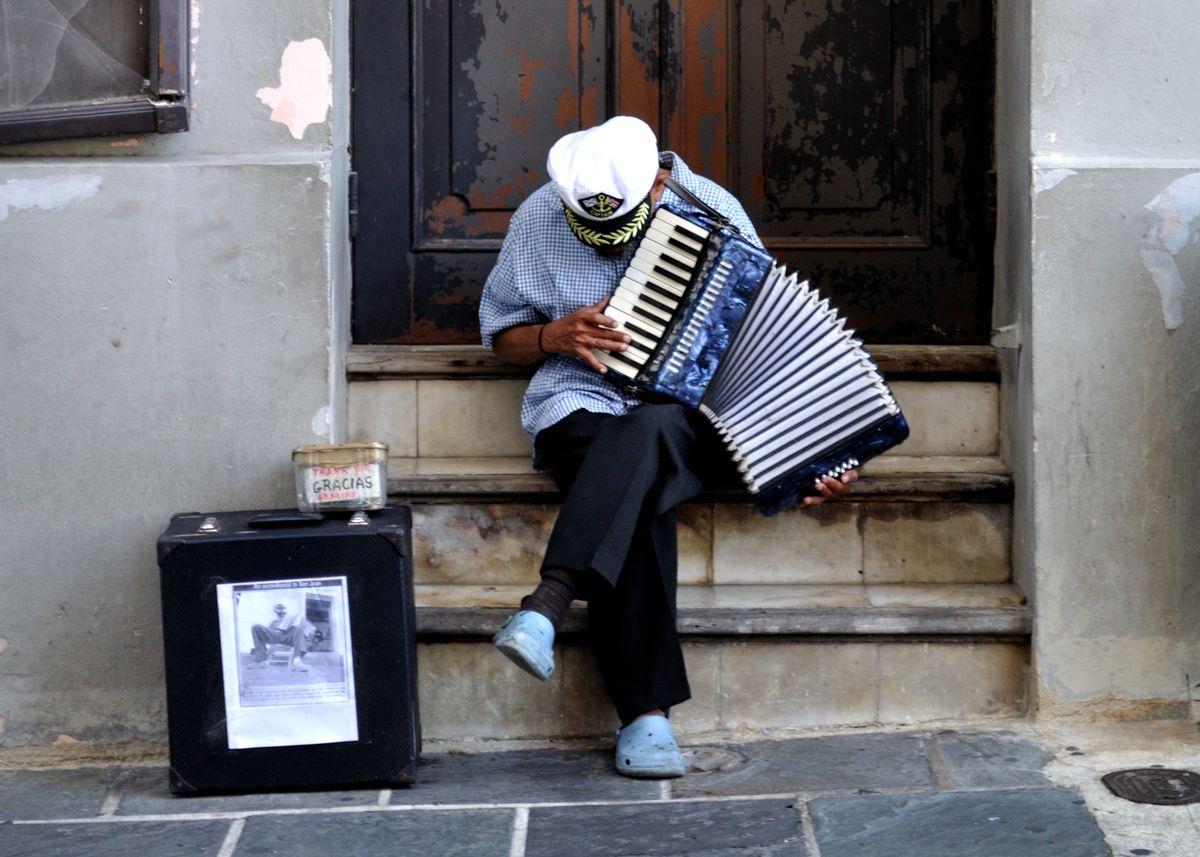 A street musician playing an accordion on a doorstep in Old San Juan, Puerto Rico